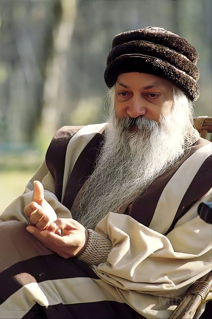 an old man with a long white beard sitting in a chair and pointing at something