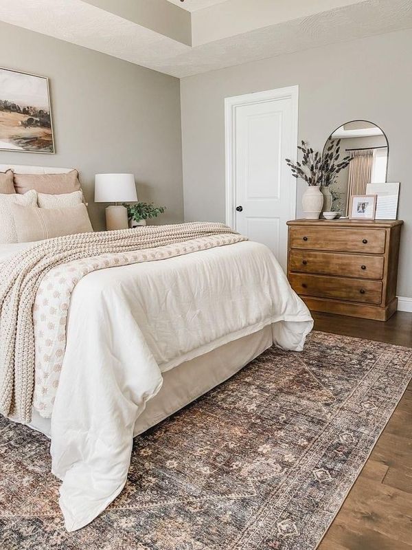 a bed sitting on top of a wooden floor next to a dresser and mirror in a bedroom