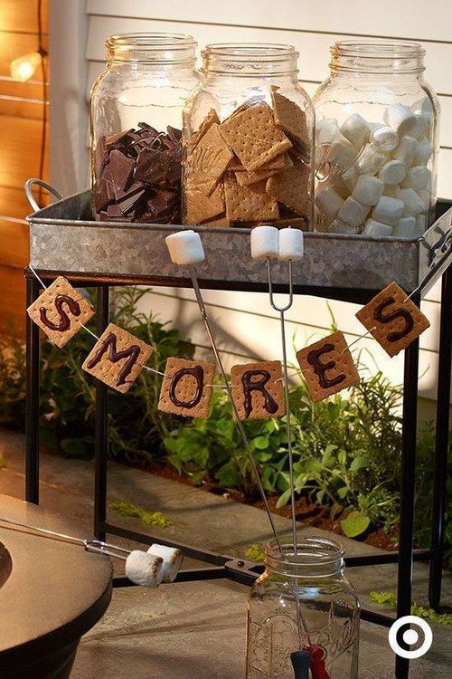 some jars with marshmallows and cookies in them sitting on a table outside