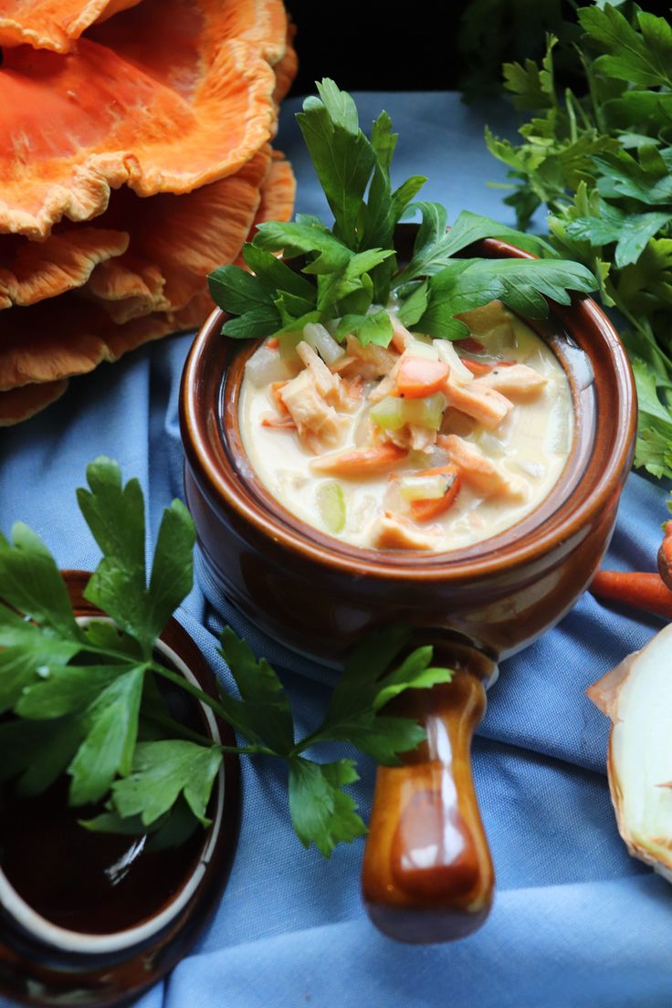 a bowl of soup with carrots, celery and parsley on the side