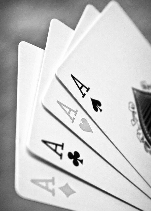 four playing cards are stacked on top of each other in black and white, with the ace symbol above them