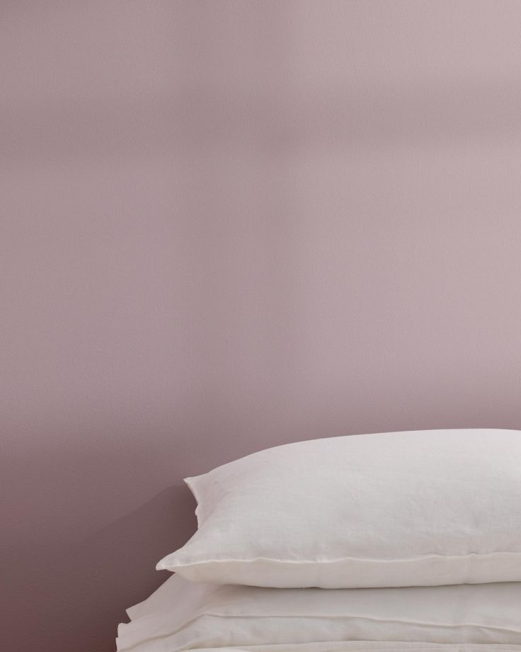 three pillows stacked on top of each other in front of a pink wall and floor