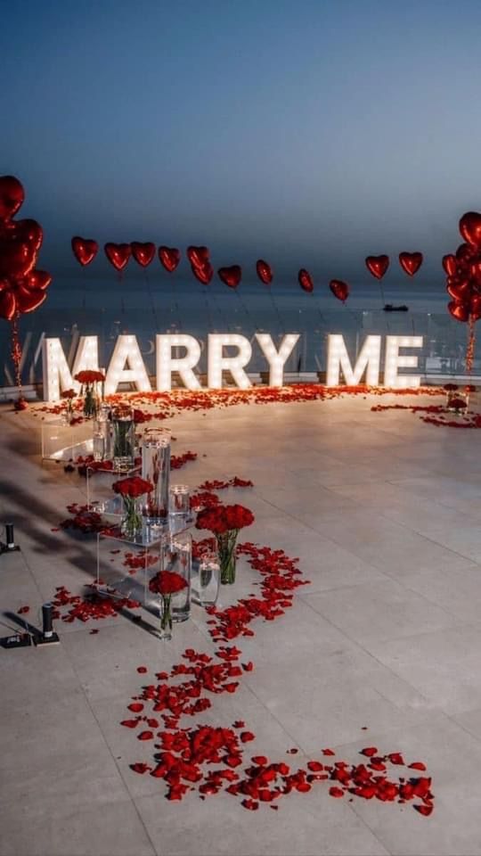 the entrance to marry me is decorated with red balloons and rose petals on the floor