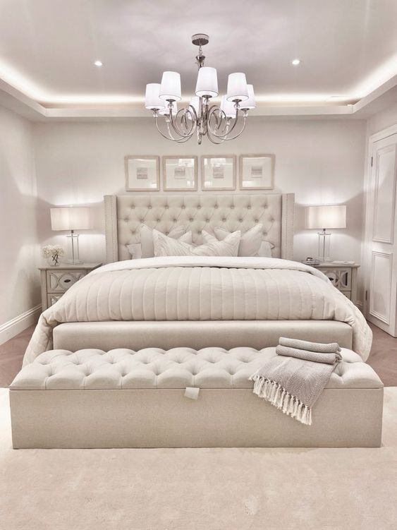 a large white bed sitting in the middle of a room with two lamps on either side of it