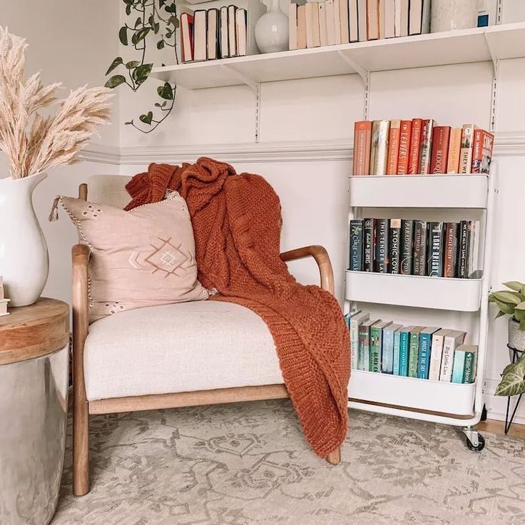 a chair with a blanket on it next to a bookshelf filled with books