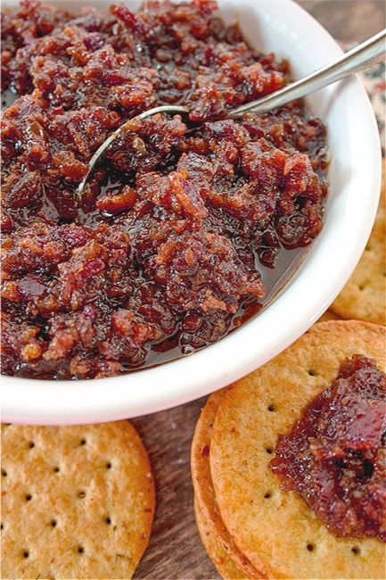 a white bowl filled with cranberry sauce next to crackers on a table