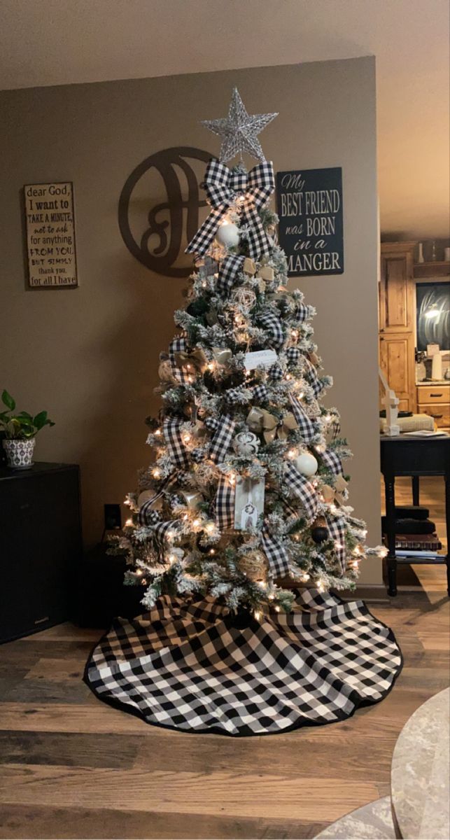 a decorated christmas tree in the corner of a living room with black and white decor