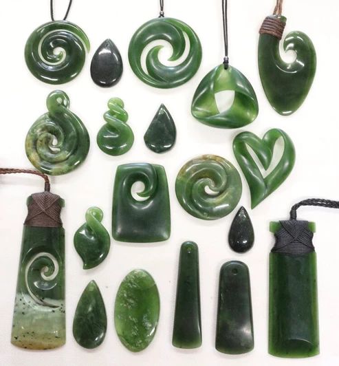 green jade pendants are displayed on a white surface with string attached to the beads