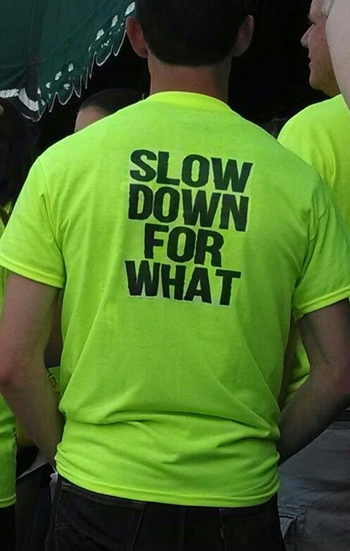 a group of people wearing neon green shirts with the words slow down for what on them