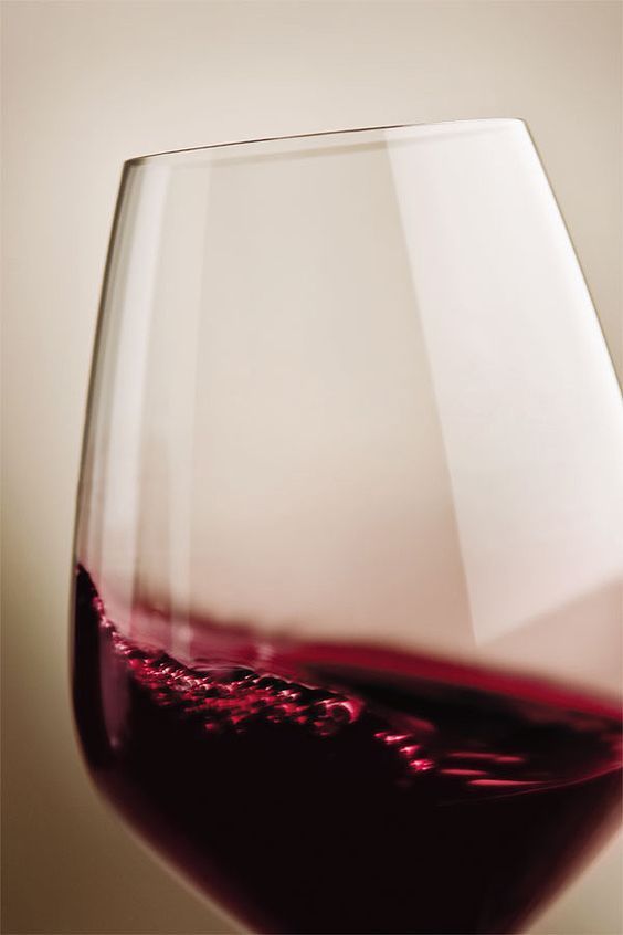 a close up of a wine glass with red wine in it's bottom half