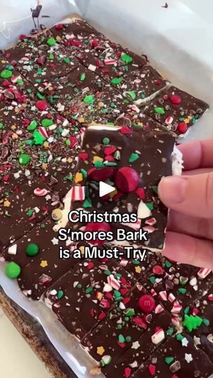 someone is decorating a christmas chocolate bark with sprinkles and candies