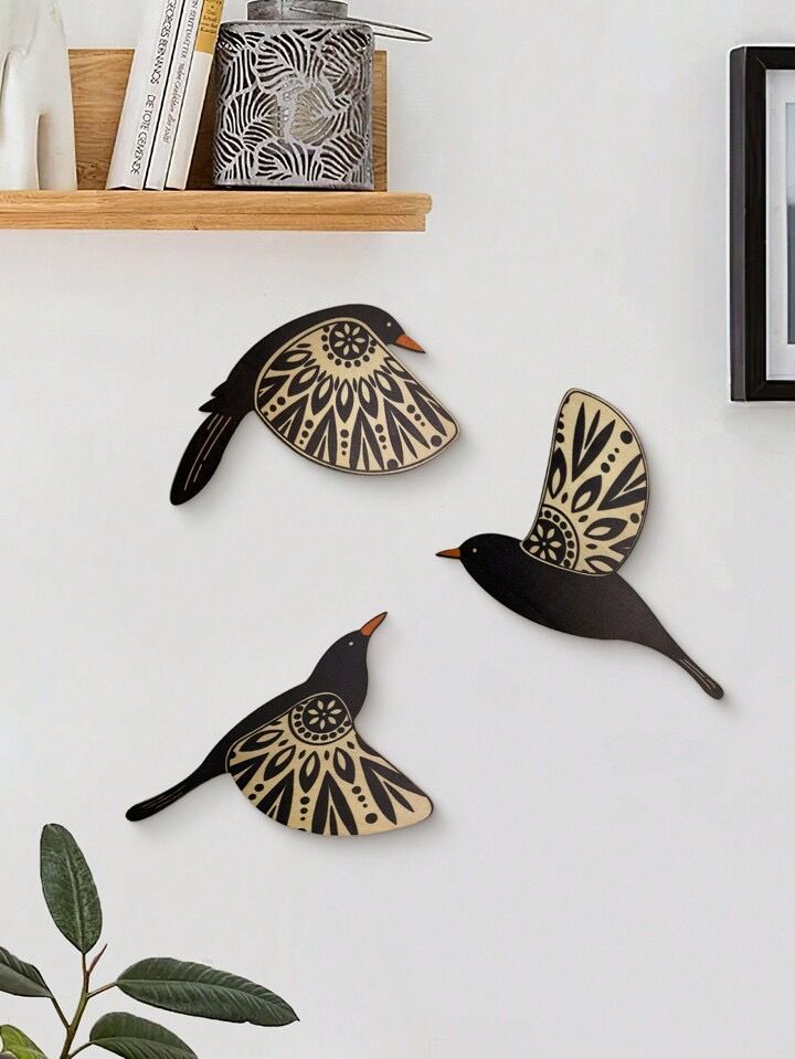 three metal birds are hanging on the wall