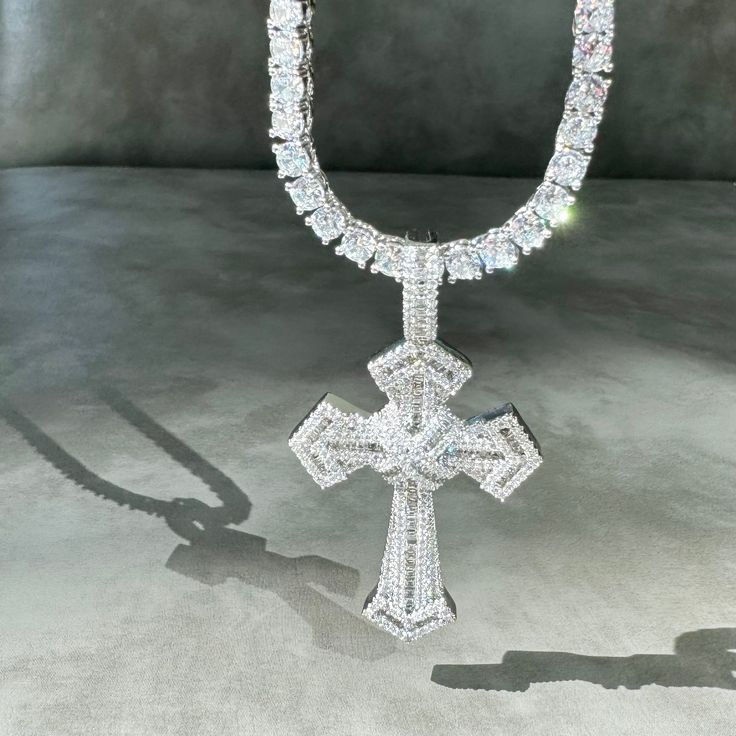 Introducing our stunning Silver Enchanted Cross Necklace! Prepare to turn heads and capture attention with its mesmerizing sparkle and shine. This necklace is truly a showstopper that exudes elegance.The focal point of this necklace is its beautiful cross pendant, meticulously paved with high-quality cubic zirconia crystals. These crystals create a dazzling effect, catching the light from every angle and reflecting it in a mesmerizing display of brilliance. The intricate detailing of the cross a Luxury Handmade German Silver Necklace, Iced Out Diamond White Cross Jewelry, Diamond Cross Necklace Iced Out, Silver Iced Out Cross Pendant Necklace, Iced Out Cubic Zirconia Cross Pendant Necklace, Iced Out Cross Necklace With Cubic Zirconia, Iced Out Diamond White Pendant Necklace, Silver Crystal Cross Pendant Necklace, White Gold Bling Cross Jewelry