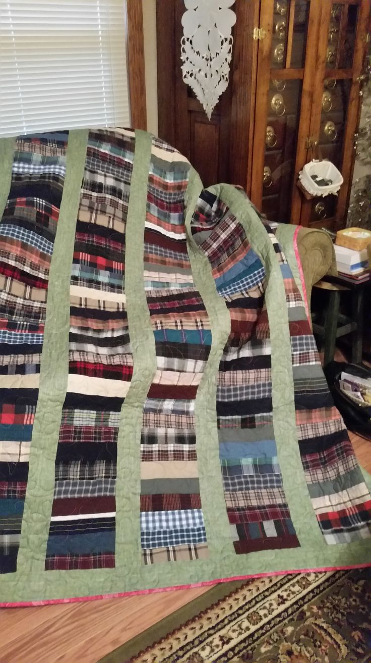 a bed with a quilt on top of it next to a rug and wooden door