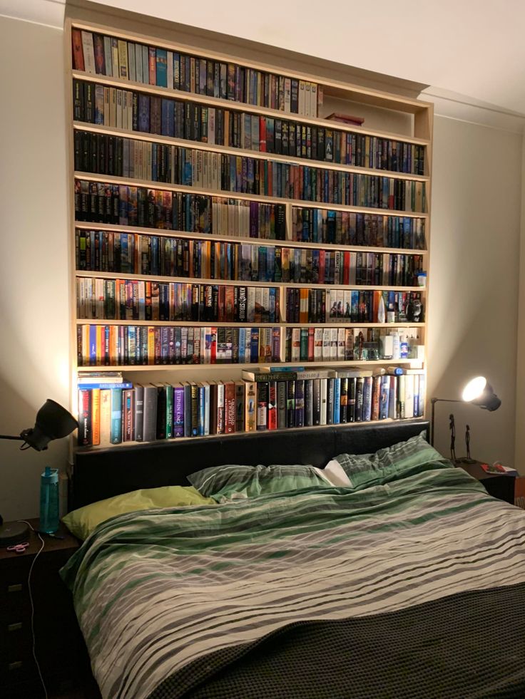 a bed sitting in front of a book shelf filled with lots of books on top of it