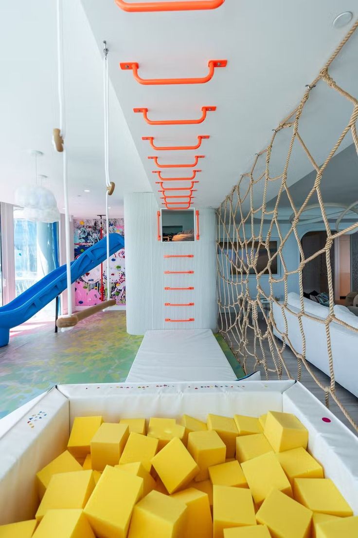 there is a room with yellow squares on the floor and a slide in the background