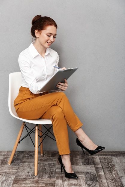 a woman sitting on a chair holding a tablet