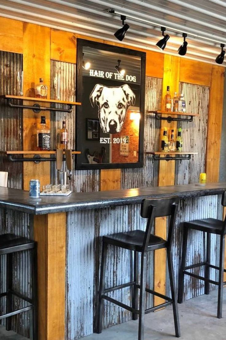 a bar with three stools in front of it and an advertisement on the wall