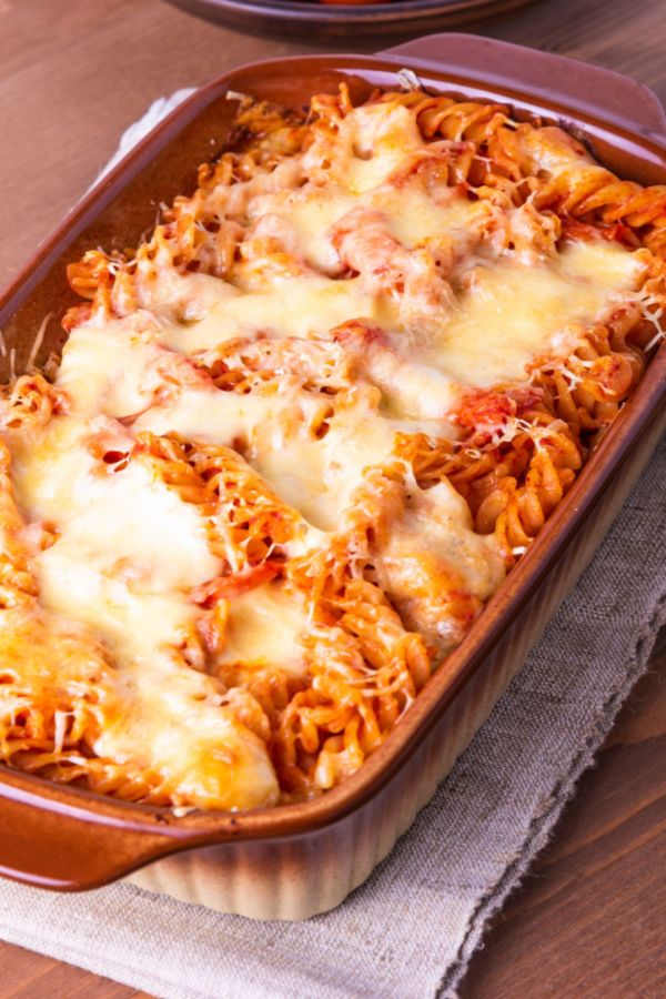 a casserole dish filled with pasta and cheese on top of a wooden table