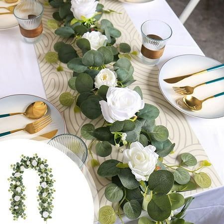 the table is set with white roses and greenery