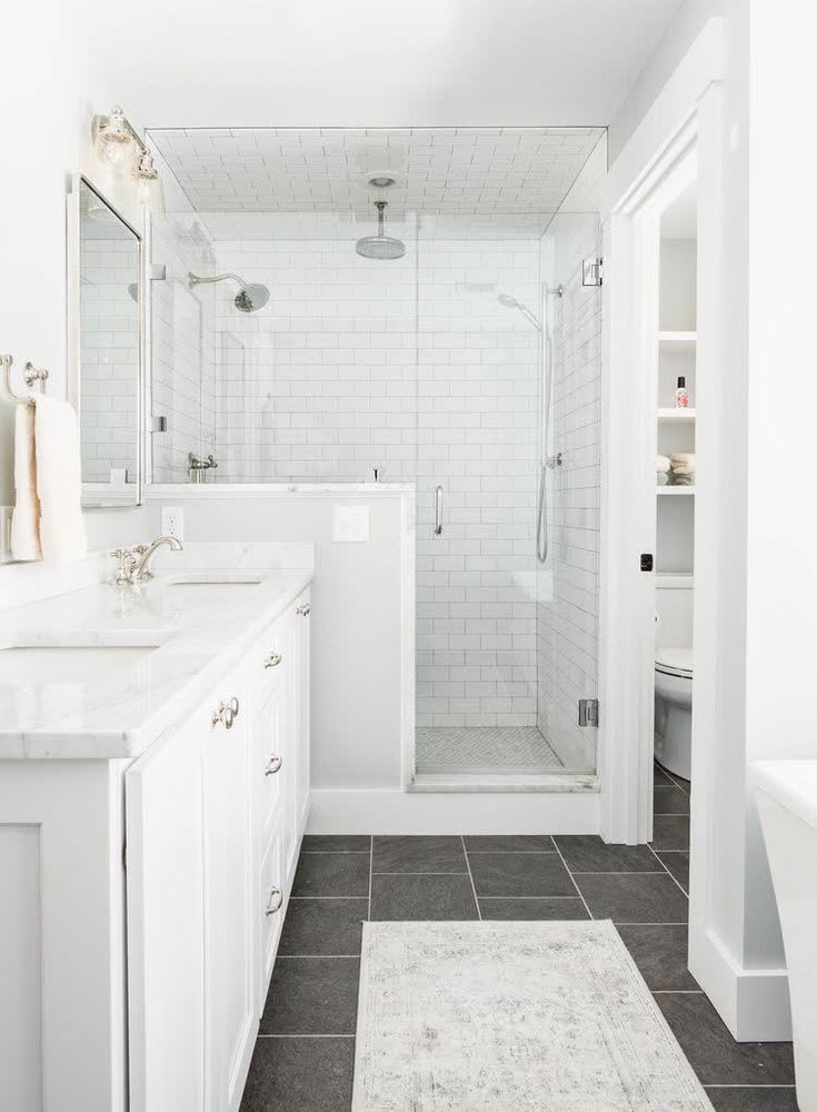 a white bathroom with two sinks and a shower