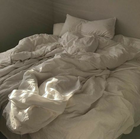 an unmade bed with white sheets and pillows