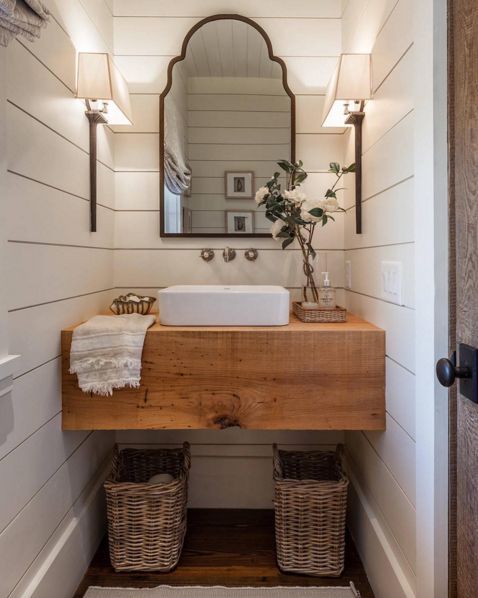 a bathroom with a sink, mirror and two wicker baskets on the floor in front of it