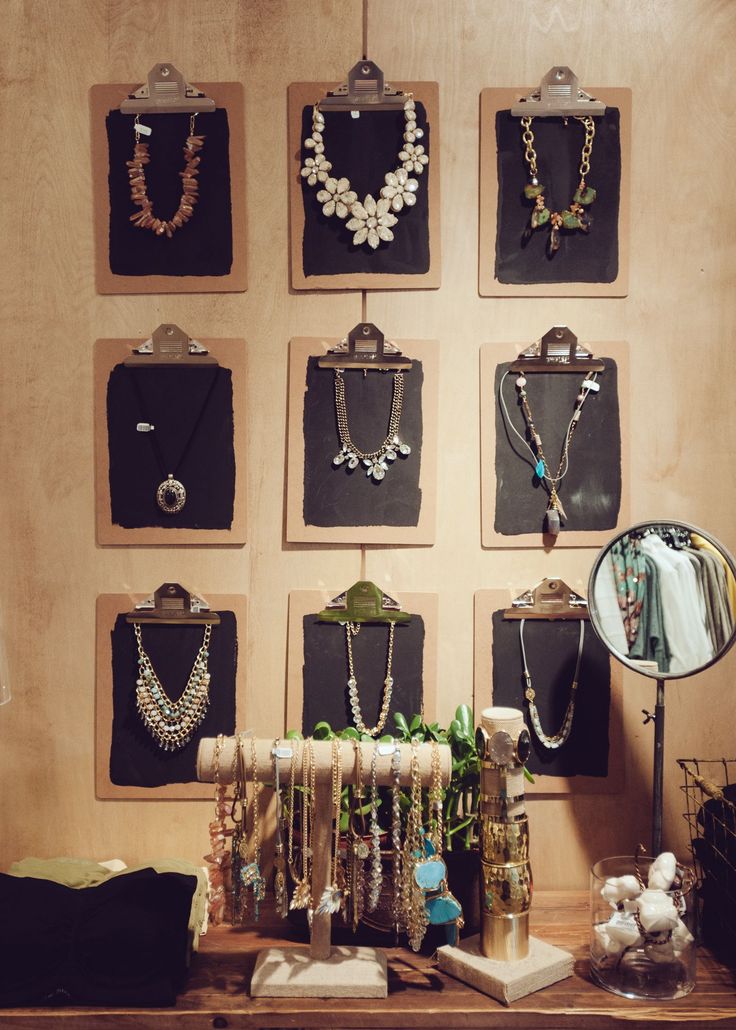 there are many necklaces hanging on the wall next to a table with a mirror