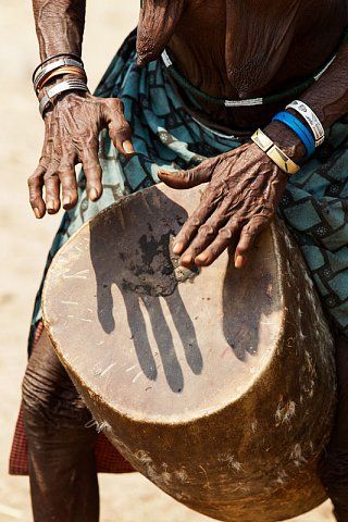 an old woman is holding a drum in her right hand and hands on the drum