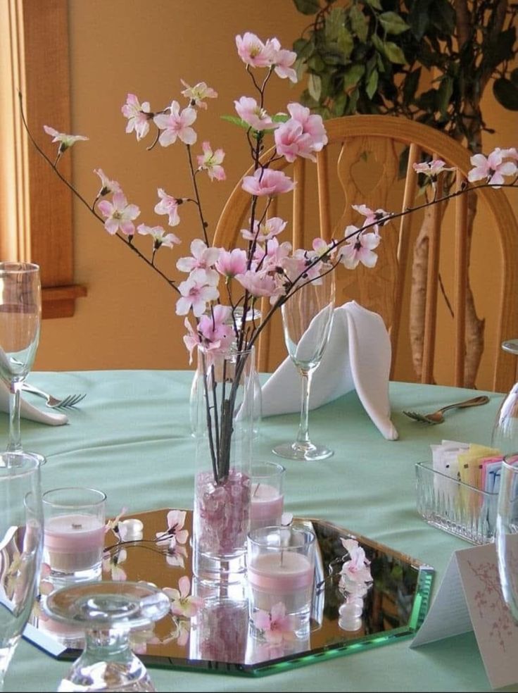 there is a vase with pink flowers in it on the table set for a party