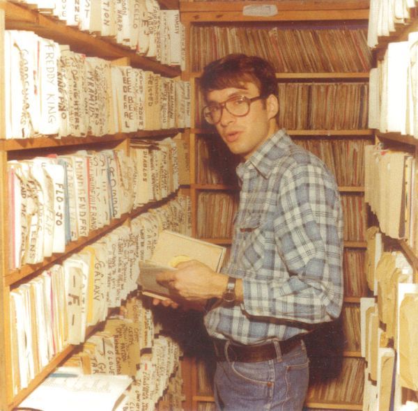 a man standing in front of a book shelf filled with books