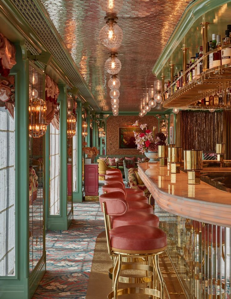 the bar is decorated with gold and red barstools, chandeliers, and wine bottles