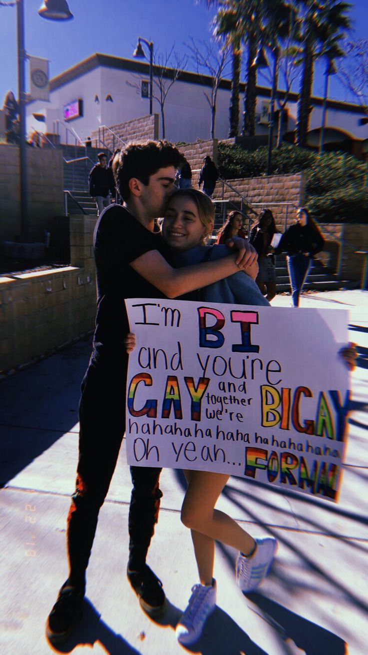 two people hugging each other while holding a sign