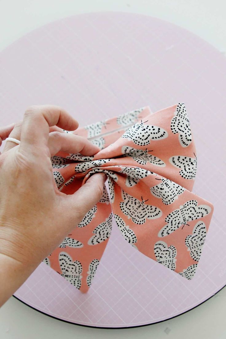 someone is tying a bow on top of a pink plate with black and white designs