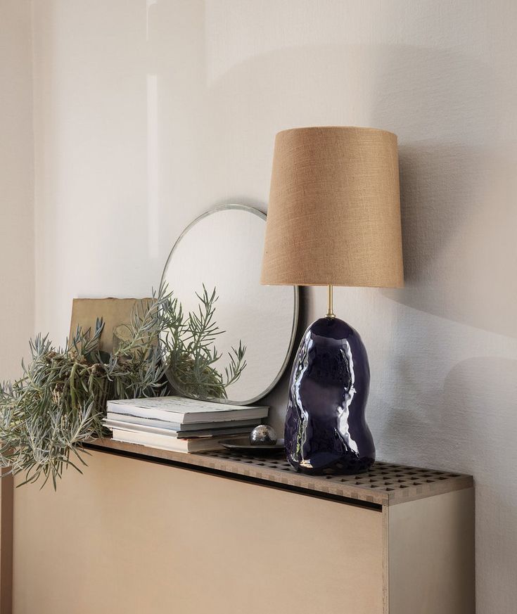 a blue vase sitting on top of a dresser next to a mirror and lamp shade