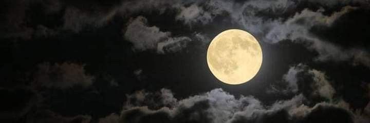 the full moon is shining brightly in the night sky with clouds and dark blue skies