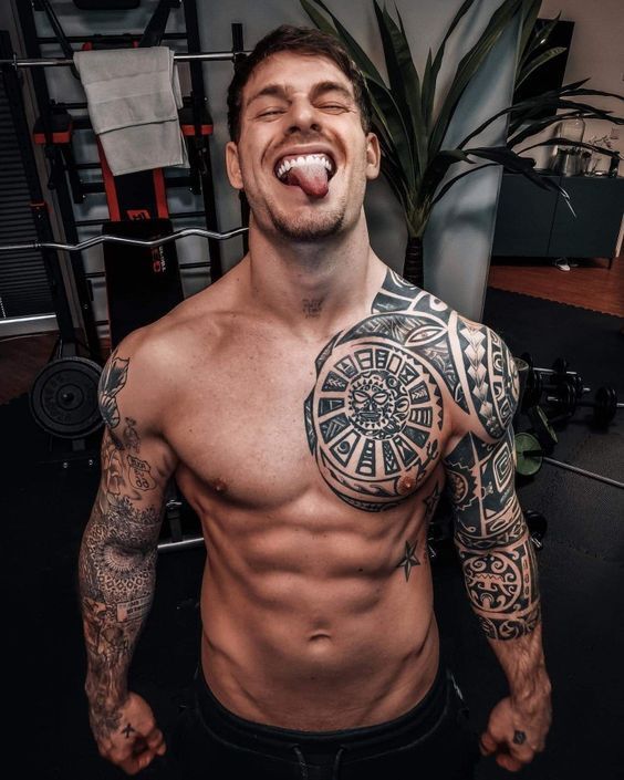 a shirtless man with tattoos on his chest and arms is posing for the camera