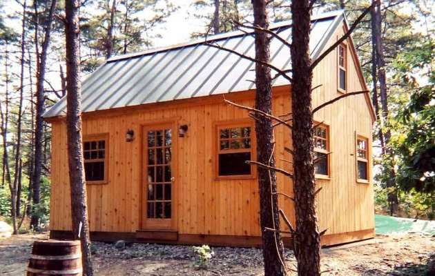 a small wooden cabin in the woods surrounded by trees