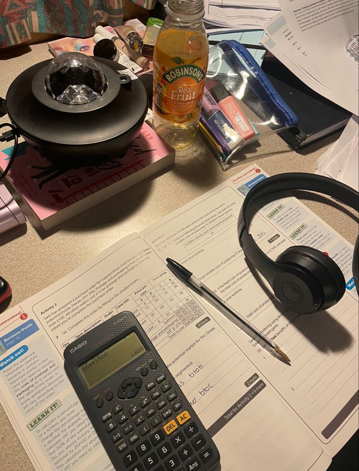 a calculator sitting on top of a desk next to headphones and papers