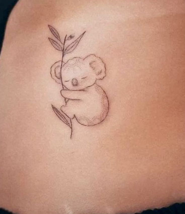 a small koala bear tattoo on the side of a woman's stomach,