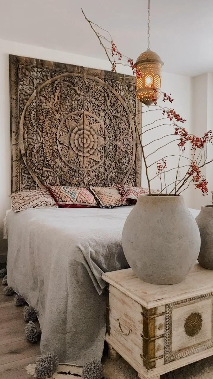 a bed with a wooden headboard and vases on the end table in front of it