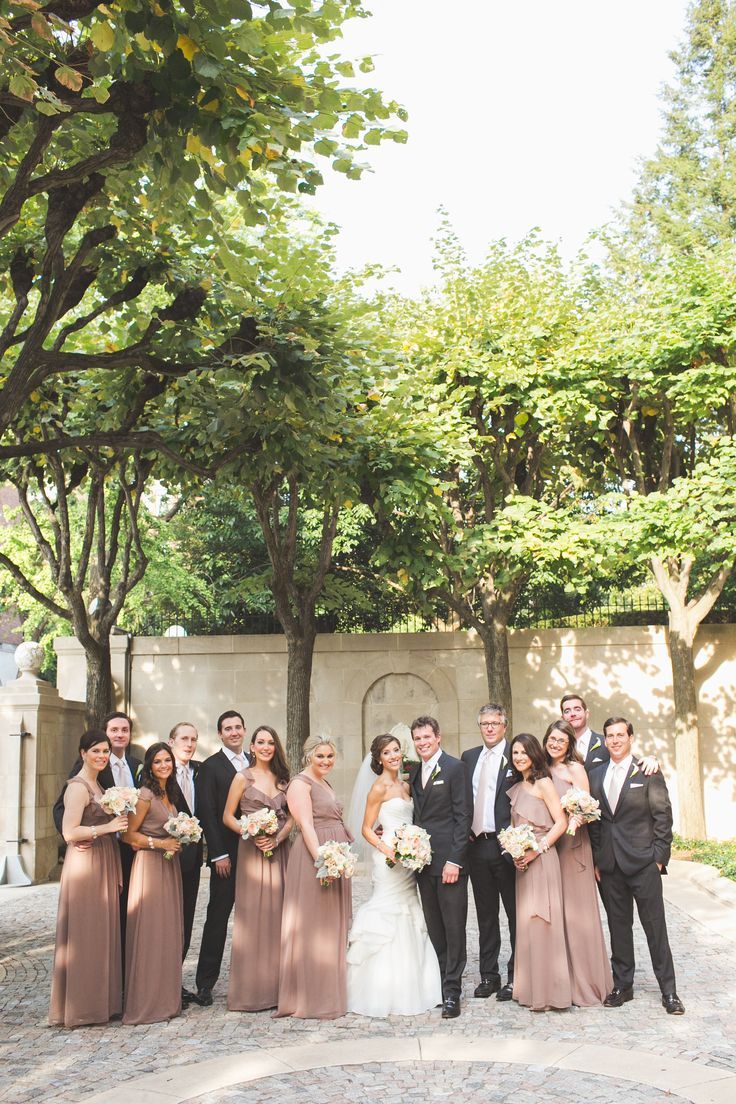 a group of people standing next to each other in front of some trees and bushes