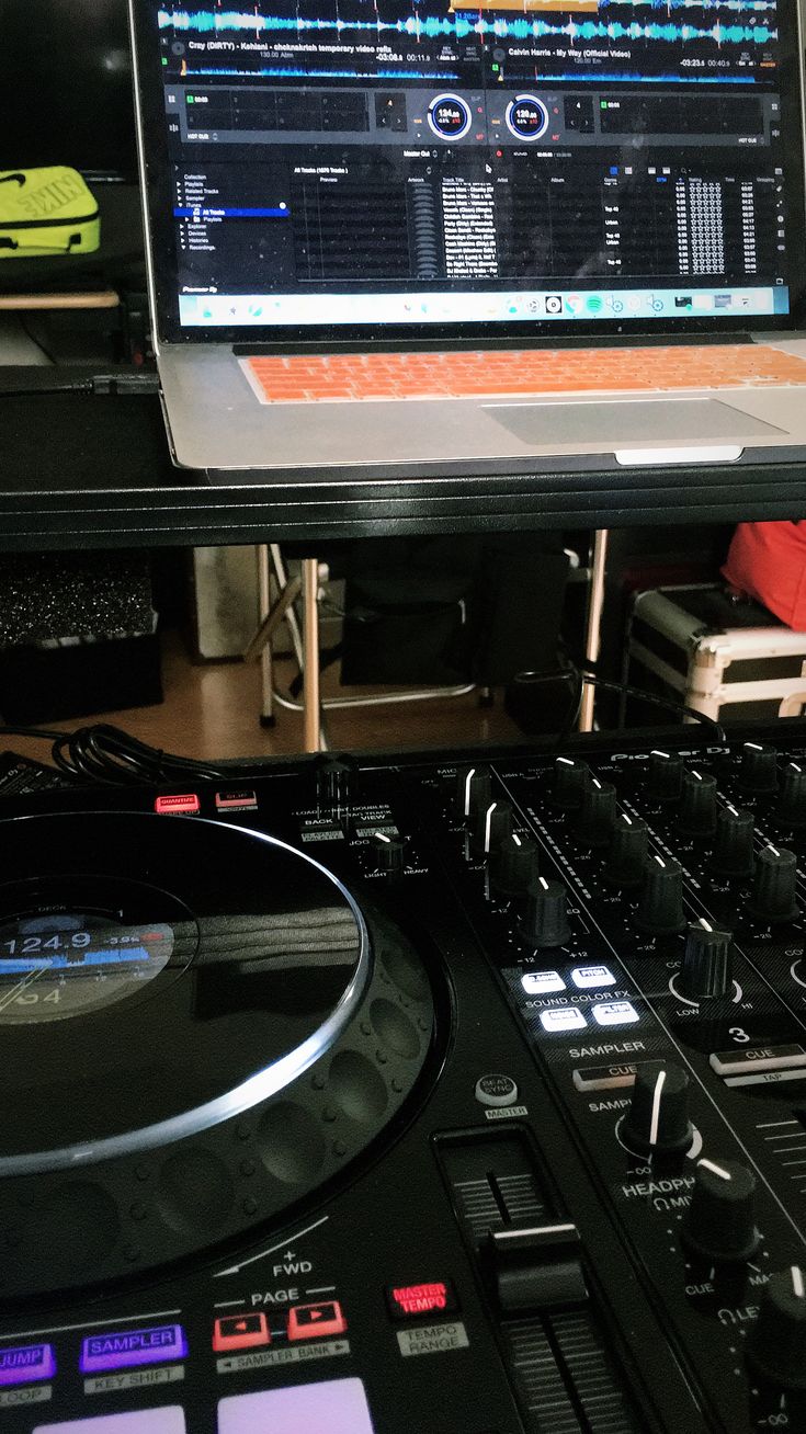 a laptop computer sitting on top of a dj's turntable in front of a monitor