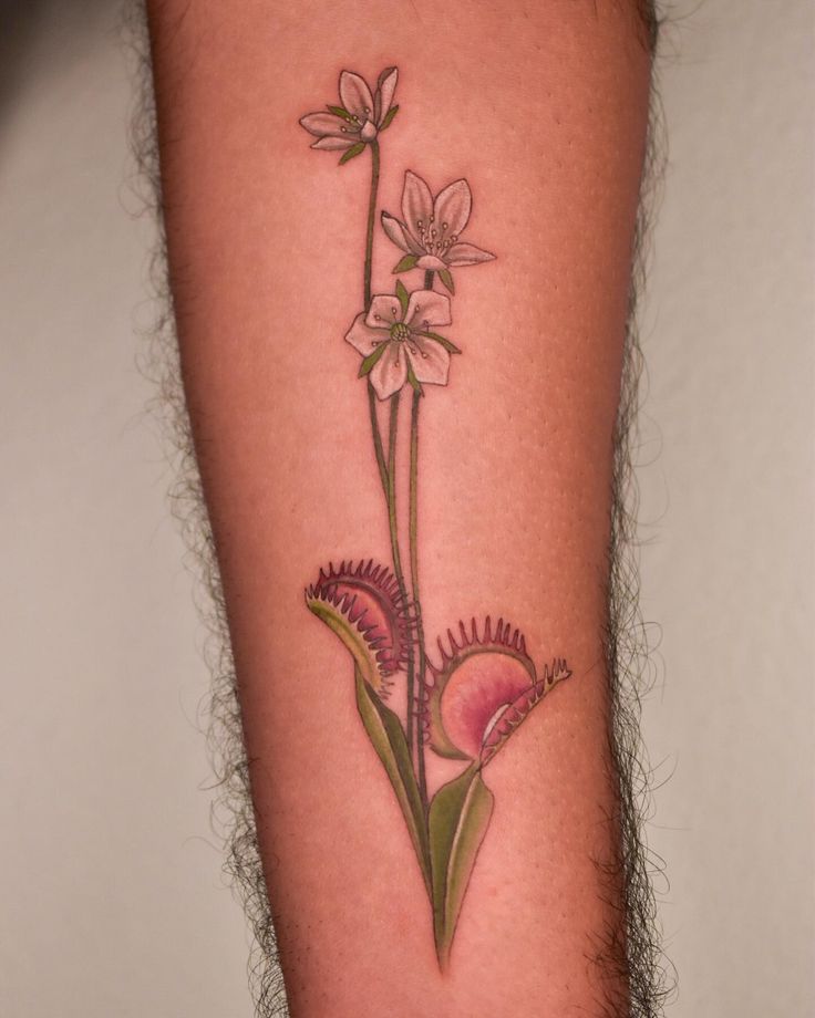 a flower tattoo on the leg of a person's arm, with pink flowers growing out of it