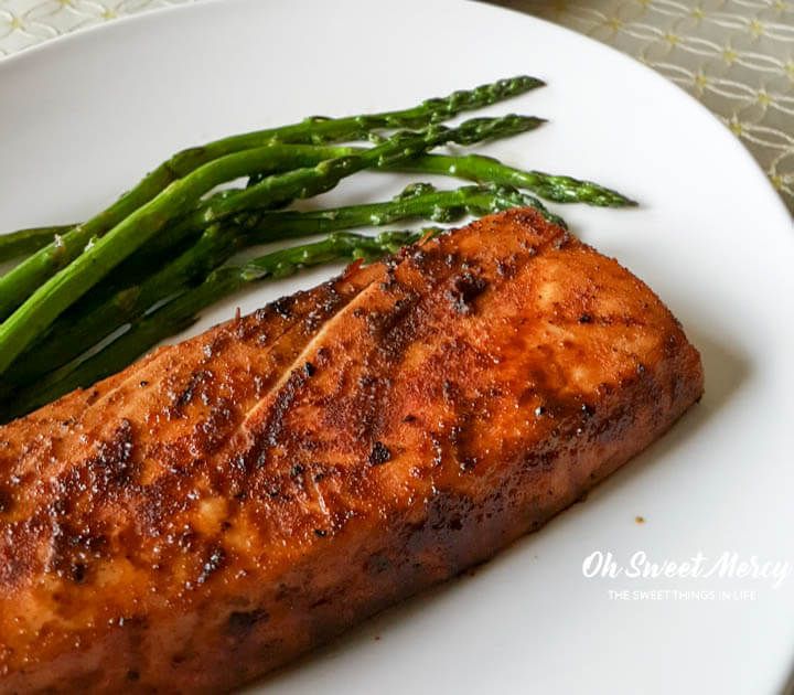 a piece of salmon and asparagus on a white plate