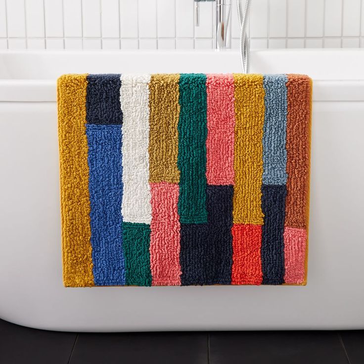 a colorful bath mat hanging on the side of a tub