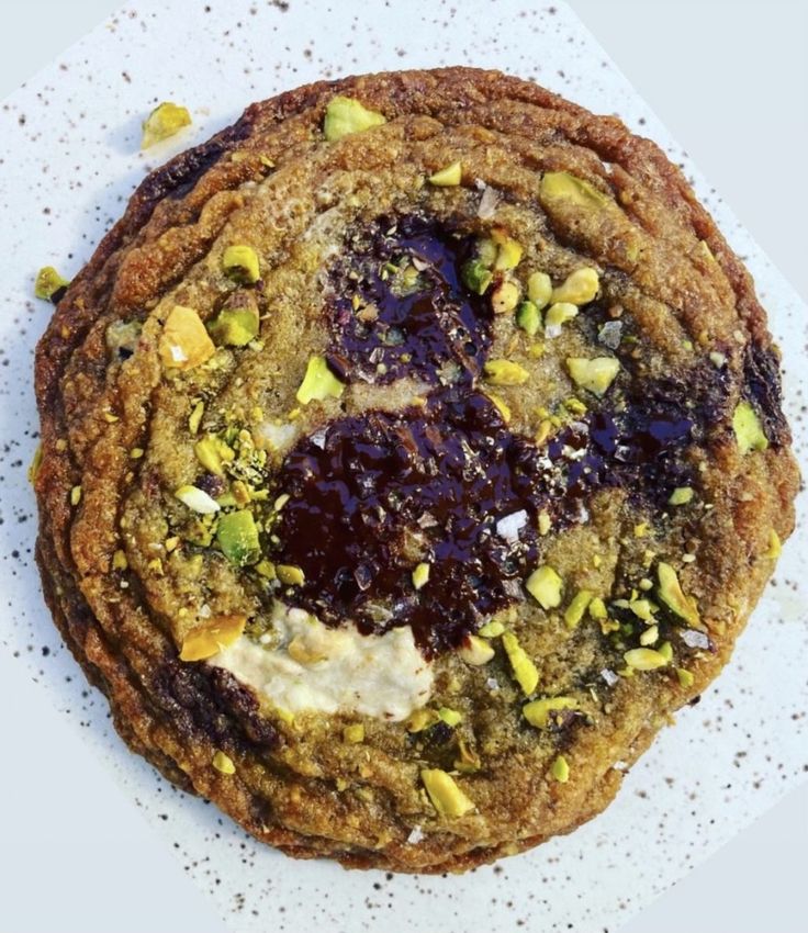 a stack of cookies sitting on top of a white plate covered in jelly and pistachio