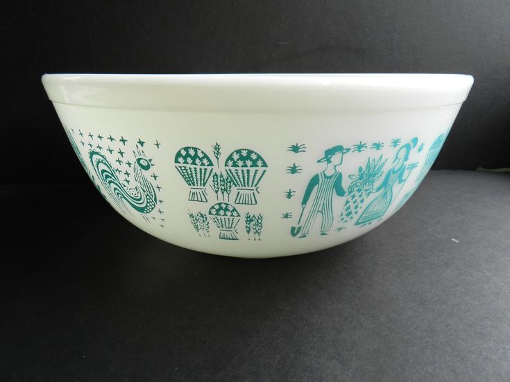 a white and blue bowl with designs on the side sitting on a black table top