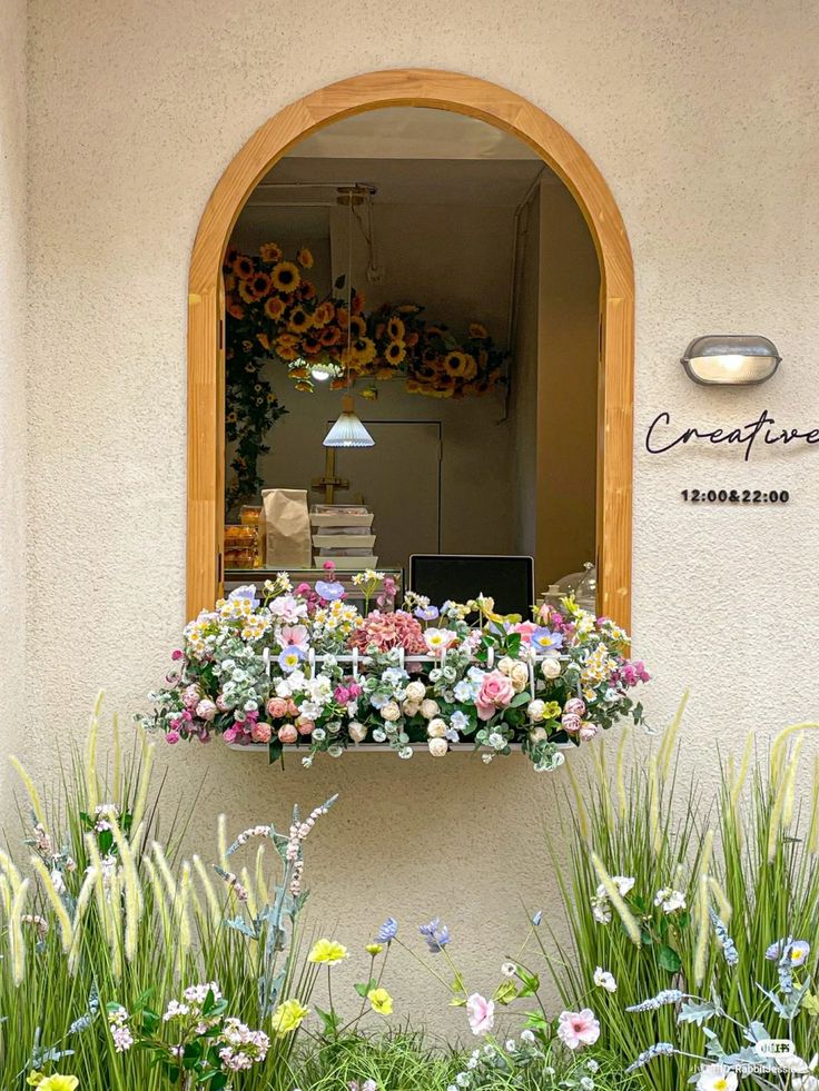 a window with flowers on it in front of a building that has an arched window