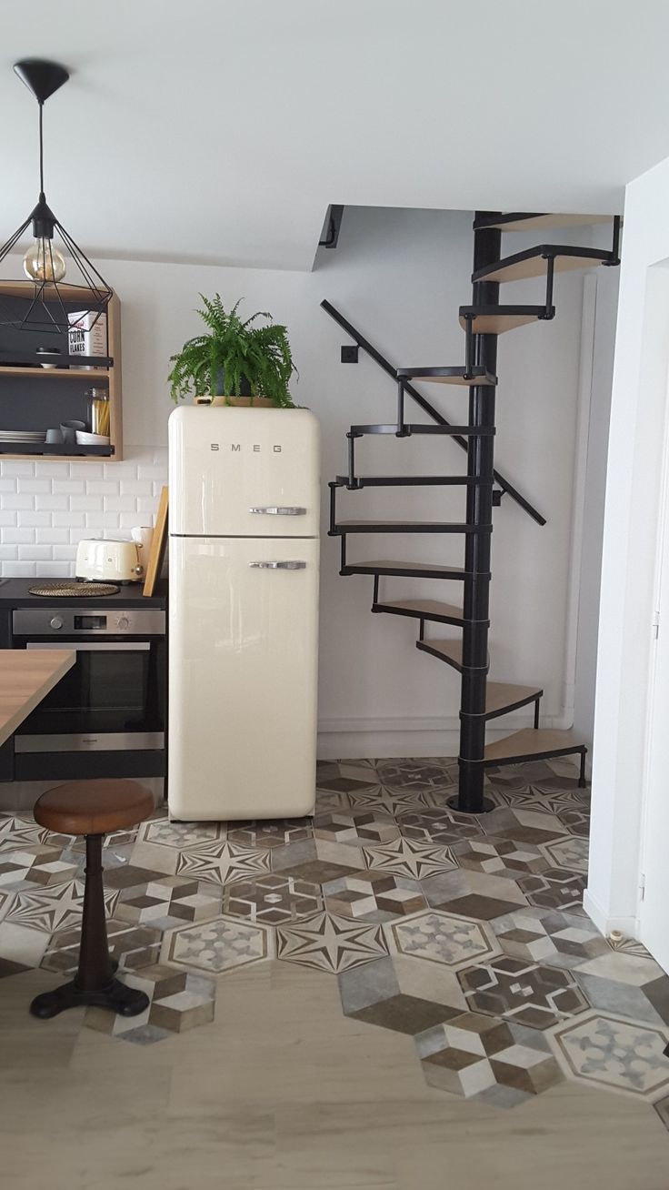 a white refrigerator sitting in the middle of a kitchen next to a spiral stair case